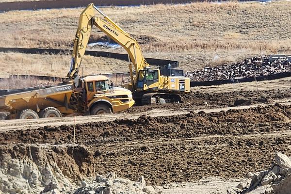 Excavator and haul truck working a cut slope