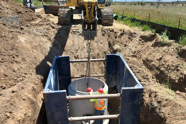 Setting a manhole inside a trench box