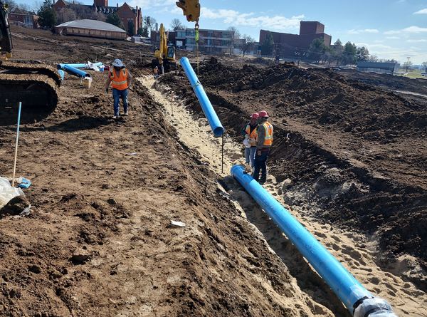 Crew laying blue PVC water main in a trench