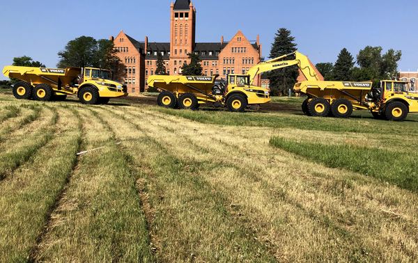 Line of SMH West haul trucks and an excavator on a Colorado project